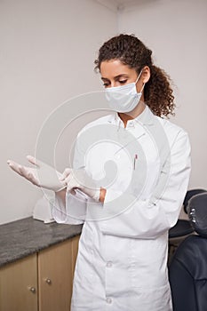 Dentist putting on surgical gloves