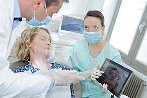Dentist with x-ray on tablet pc computer and girl patient