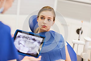 Dentist with x-ray on tablet pc and girl patient