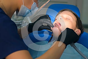 Dentist rinses boy mouth water holding saliva ejector on oral hygienic cleaning.