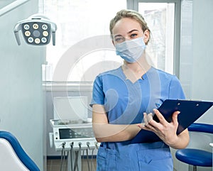 Dentist& x27;s assistant or female dentist in protective face mask on the background of dentistry room