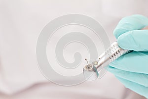 Dentist`s hand in an examination glove with dental handpiece