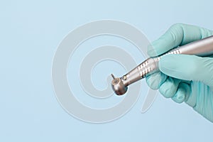 Dentist`s hand in glove with dental handpiece