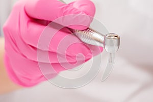Dentist`s hand in glove with dental handpiece