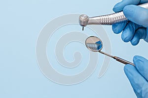 Dentist`s hands in glove with dental handpiece and mouth mirror