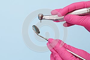 Dentist`s hands in gloves with dental handpiece and mouth mirror