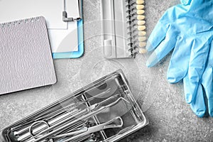 Dentist's tools, gloves and teeth color samples on light background