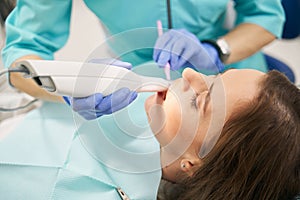 Dentist scanning female teeth with dental 3D scanner