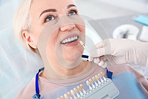 Dentist selecting patient`s teeth color with palette