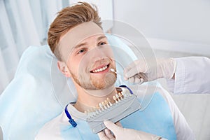 Dentist selecting patient`s teeth color with palette