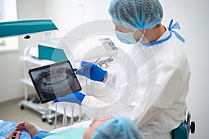 Dentist showing dental x ray to patient in clinic