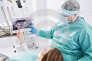 Dentist showing dental scan to woman in stomatology clinic