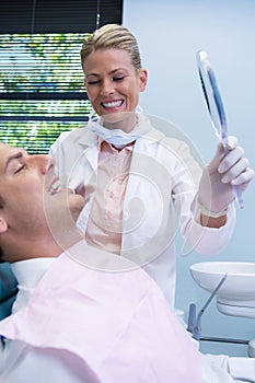 Dentist showing mirrior to patient