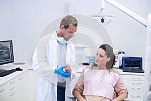 Dentist showing model teeth to patient