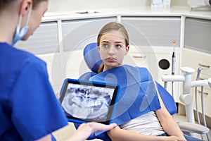 Dentist showing x-ray on tablet pc to patient girl