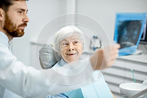 Dentist showing x-ray to the elder woman in the dentall office