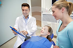 Dentist showing tablet pc to girl and her mother