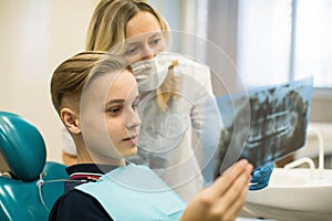 Dentist showing to boy patient x-ray the jaw at dental clinic