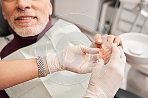 Dentist showing to her patient teeth dentures