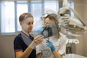 Dentist showing to patient x-ray the jaw at medical clinic.