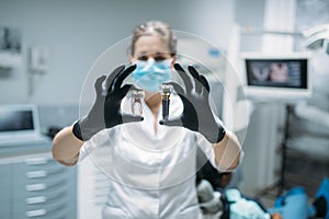 Dentist shows tooth pin and model, dental clinic