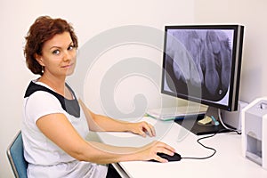 Dentist sits at table with jaw x-ray image