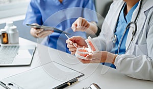 Dentist sitting at table with jaw samples tooth model and working with tablet and laptop in dental office professional dental