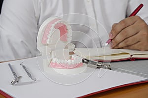 Dentist sitting at table with tooth model and tools in professional dental clinic, dental and medical concept