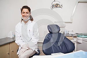 Dentist smiling at camera beside chair