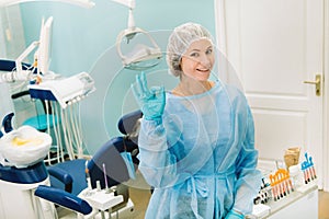 Zubár stojí vo svojej ordinácii a ukazuje znak OK