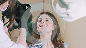 A dentist takes a photograph of the patient`s smile after the work done. The specialist cured the girl`s teeth and takes