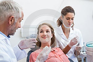 Dentist talking with patient while nurse prepares the tools