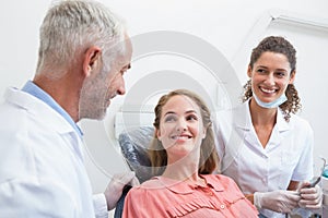 Dentist talking with patient while nurse prepares the tools