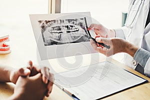 Dentist talking to male patient and presenting results on Dental x-ray film About the problem of the patient in dental office photo