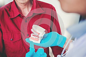 Dentist talking to smiling male patient and showing denture in dental office photo