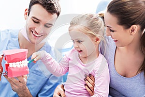 Dentist teaching girl how to brush teeth