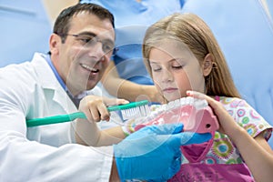 Dentist teaching girl how to properly brush her teeth