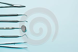 Dentist tools on blue background: corncang, curette, dental probe, gross-mayer clamp, dental mirror and explorer. Dental hygiene a