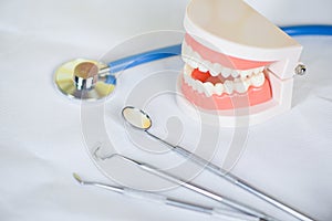 Dentist tools with dentures dentistry instruments and dental hygienist checkup concept with teeth model and mouth mirror oral