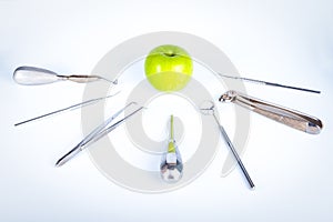 Dentist tools in front of green apple