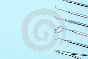 Dentist tools on light blue background: kornzange, curette, dental probe, gross-mayer clamp, dental mirror and explorer. Dental