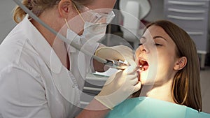 Dentist treating teeth to woman patient in clinic. Female professional doctor at work. Dental checkup