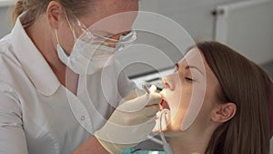 Dentist treating teeth to woman patient in clinic. Female professional doctor at work. Dental checkup