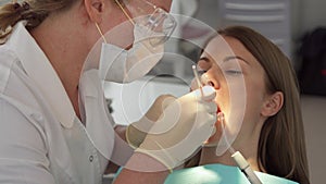 Dentist treating teeth to woman patient in clinic. Female professional doctor at work. Dental checkup