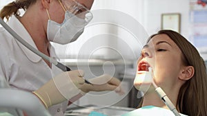 Dentist treating teeth to woman patient in clinic. Female professional doctor at work. Dental checkup