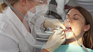 Dentist treating teeth to woman patient in clinic. Female professional doctor at work. Dental checkup