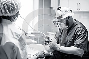 Dentist treating teeth to young woman patient in clinic.