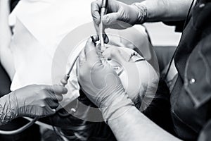 Dentist treating teeth to young woman patient in clinic.