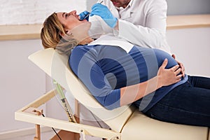 Dentist Treating Teeth Of Young Pregnant Woman Patient Lying