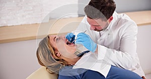 Dentist Treating Teeth Of Young Pregnant Woman Patient Lying